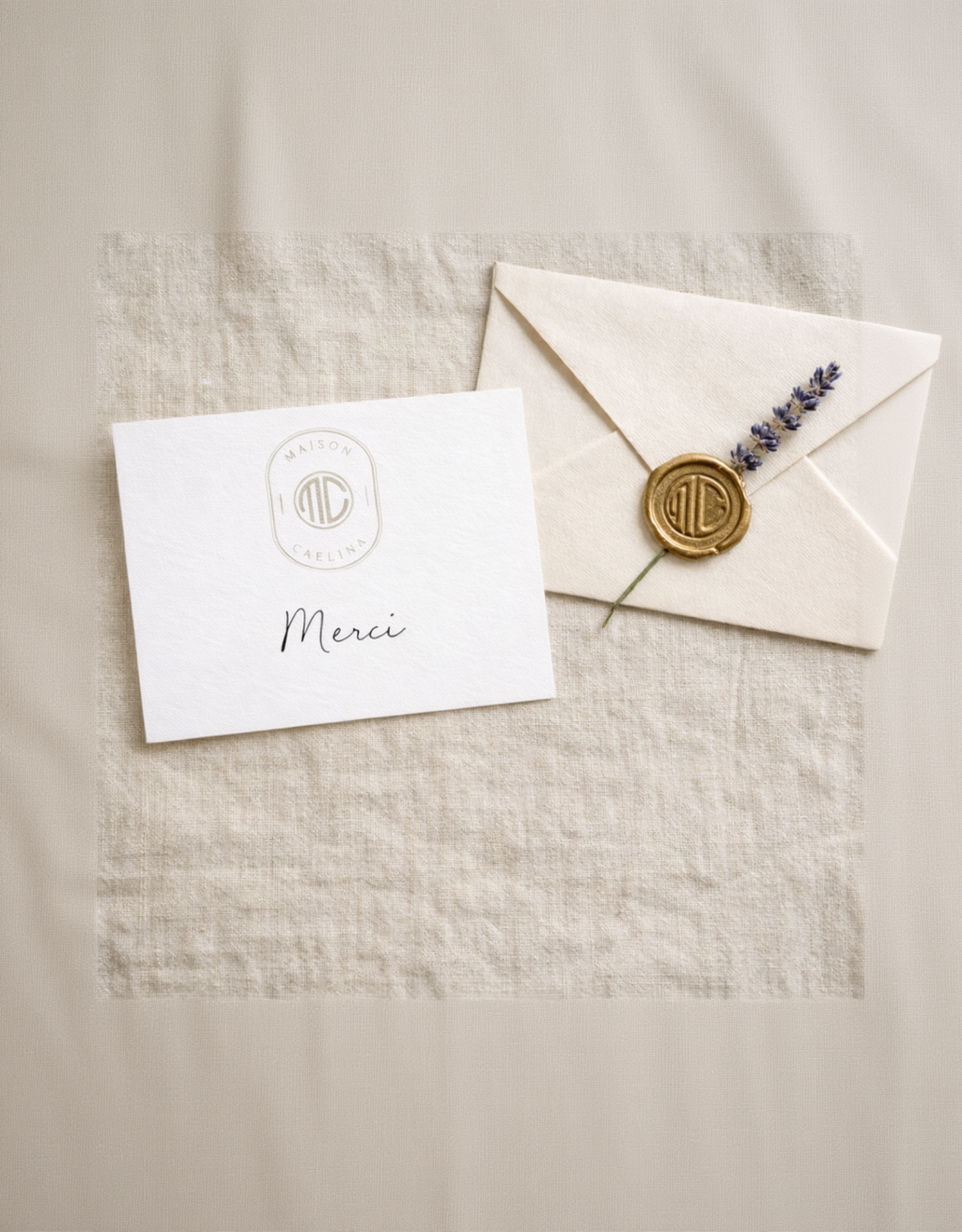 White card with 'Merci' and a wax seal Maison Caelīna MC on a beige fabric background