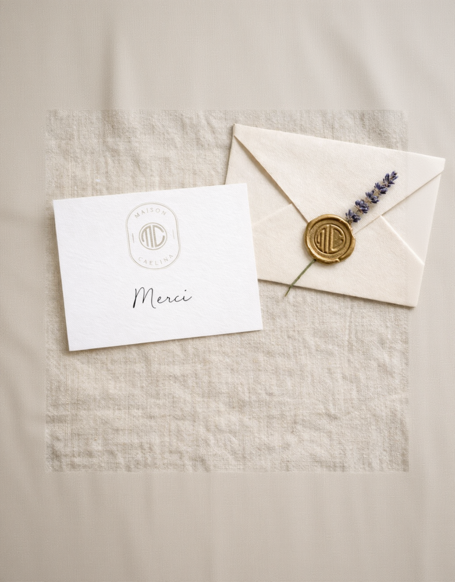 White card with 'Merci' and a wax seal Maison Caelīna MC on a beige fabric background